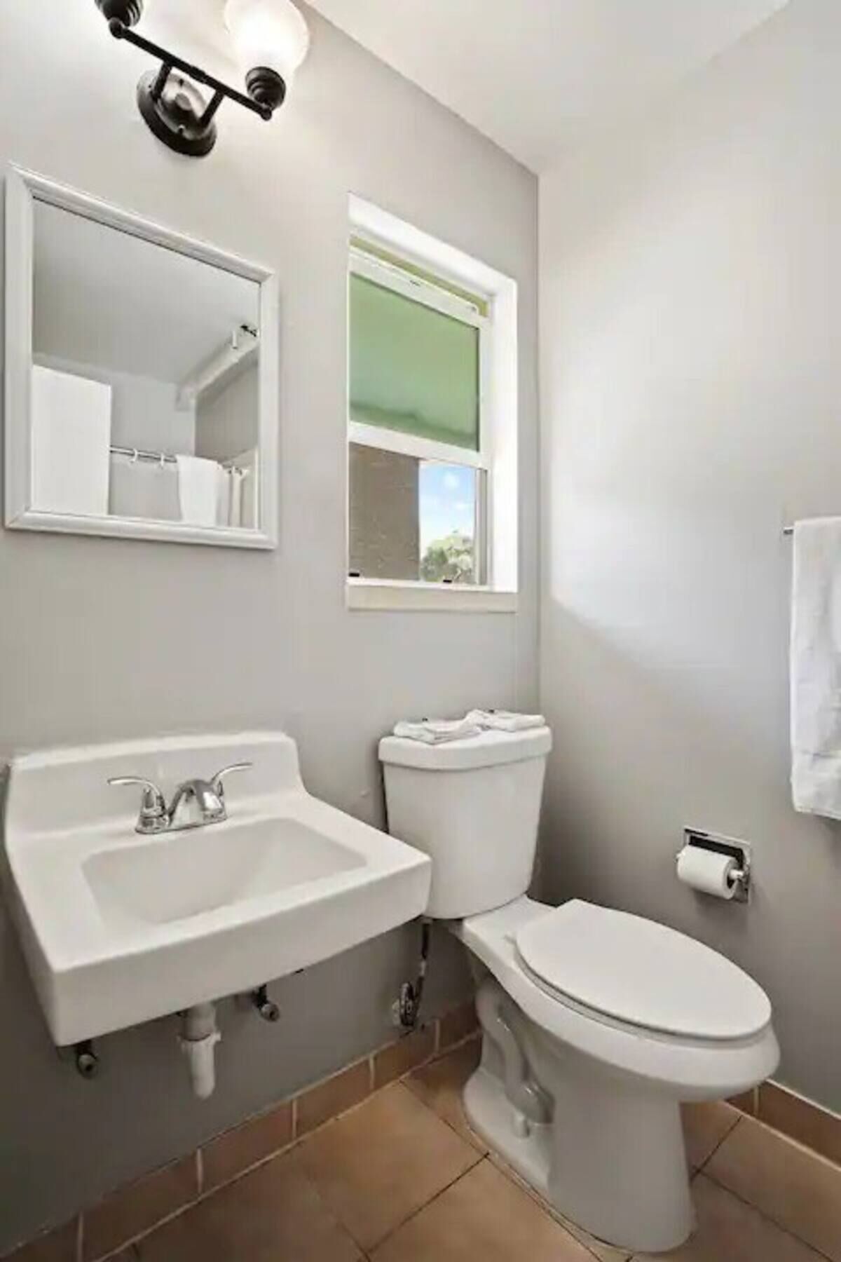 A bathroom with a sink, toilet, and mirror.
