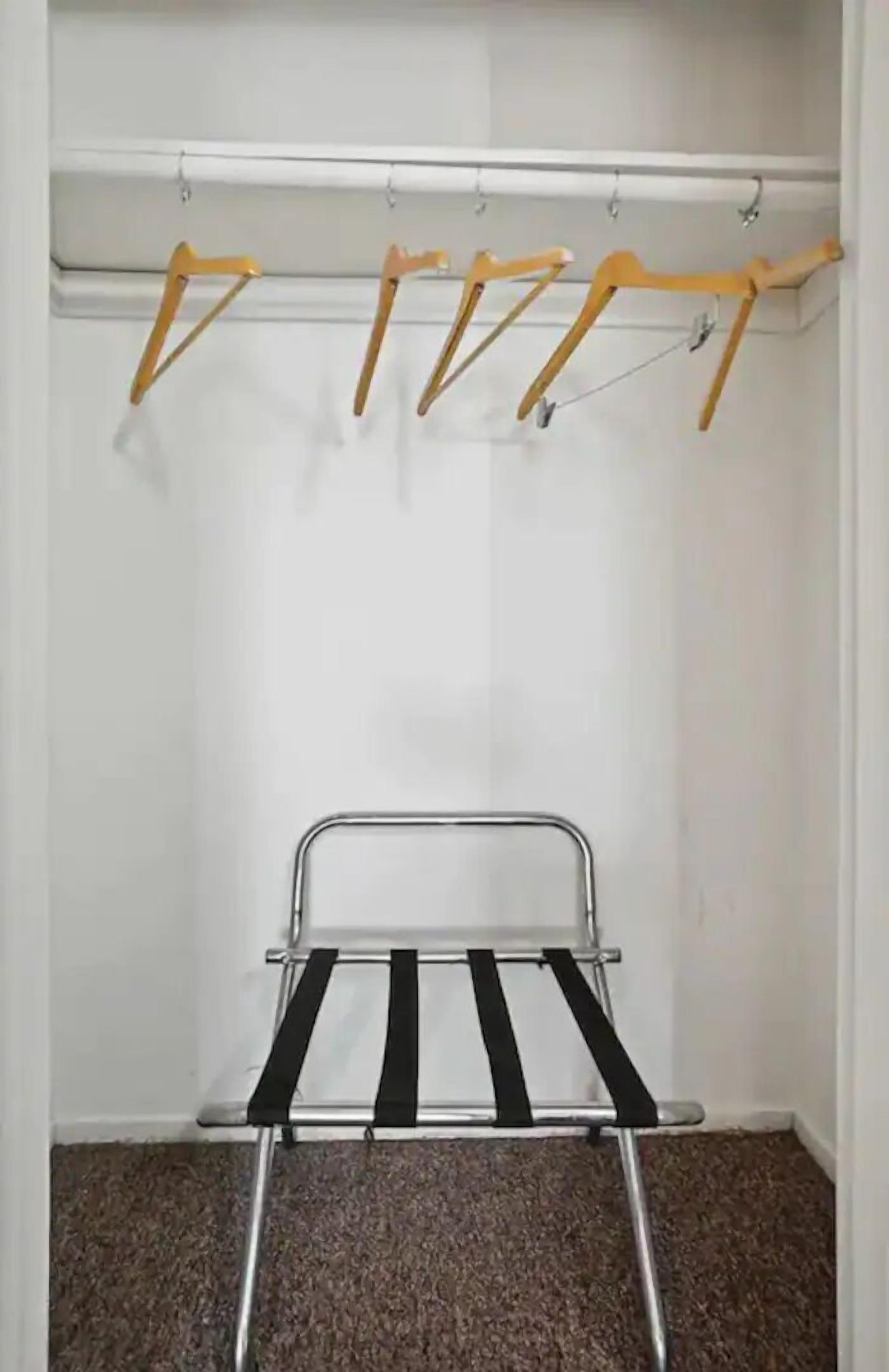A room with a metal drying rack and wooden hangers on a wall-mounted rack.