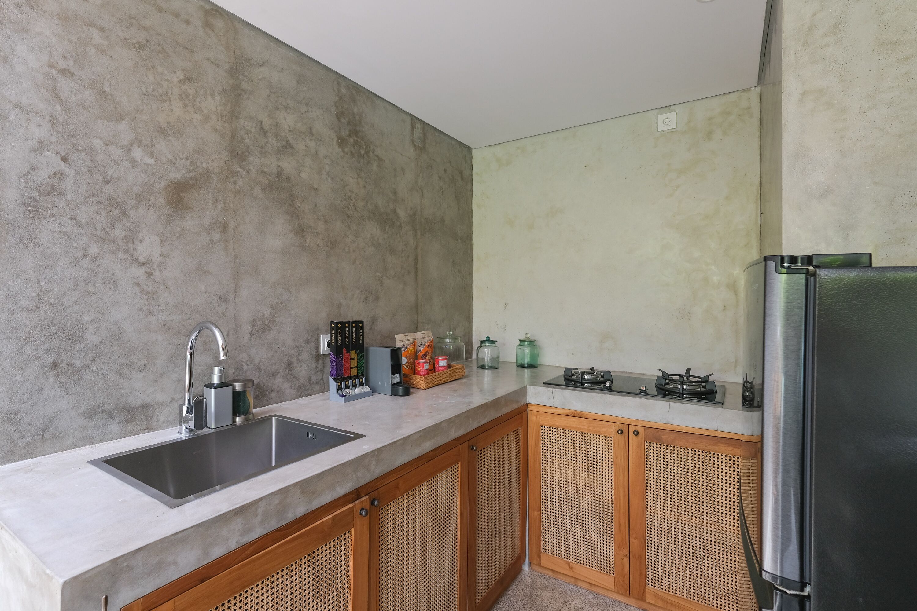 A kitchen with a stainless steel sink, wooden cabinets, a gas stove, and a refrigerator.