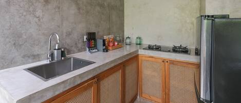 A kitchen with a stainless steel sink, wooden cabinets, a gas stove, and a refrigerator.