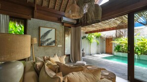 Un salón moderno con sofá, lámpara y un ventanal con vistas a una zona de piscina.