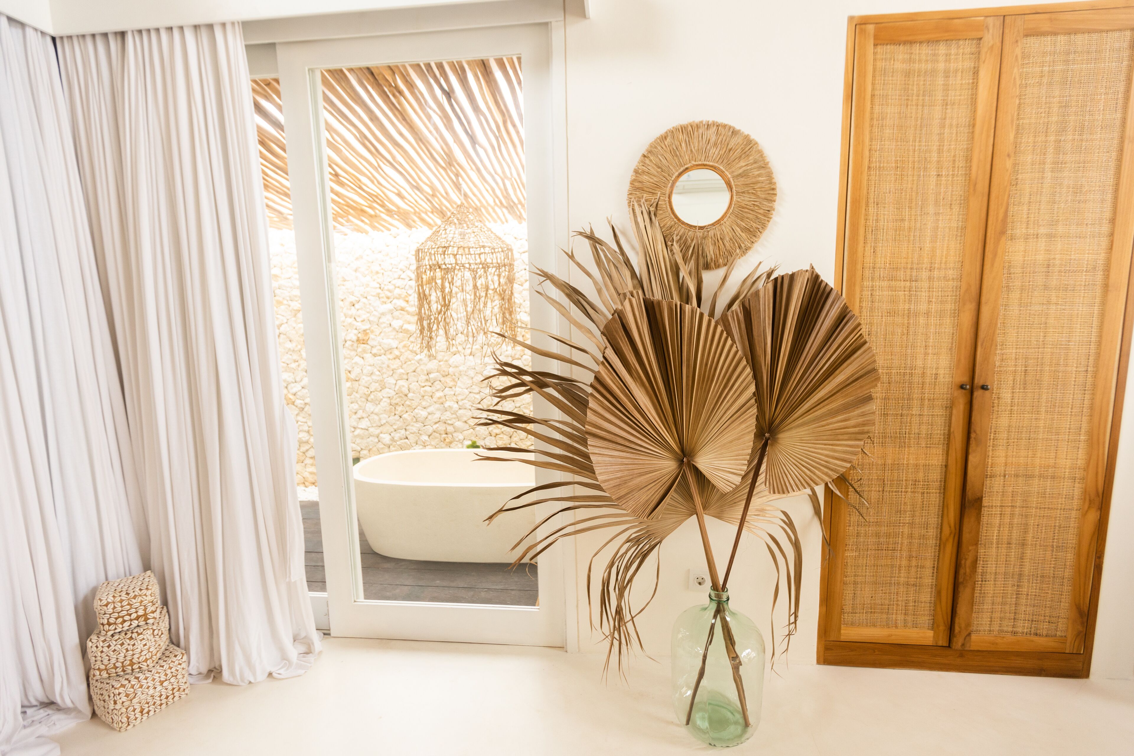 A bathroom with a bathtub, a large mirror, and a wooden door.