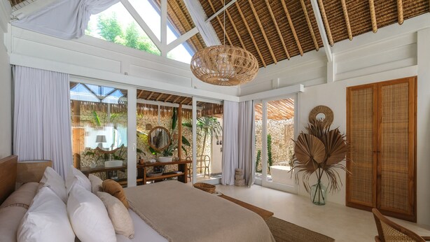 Un dormitorio espacioso con una cama grande, una lámpara de techo de mimbre y vistas al exterior.