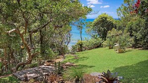 A lush garden with a clear view of the ocean.