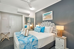 Relax in a serene bedroom with a large bed, a bedside table, and a large mirror.