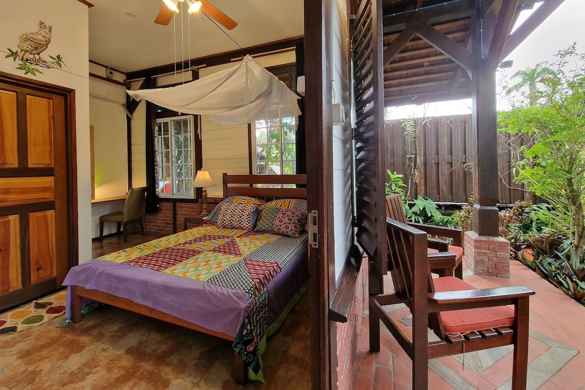 A bedroom with a bed, a ceiling fan, a window, and a view of the outdoors.