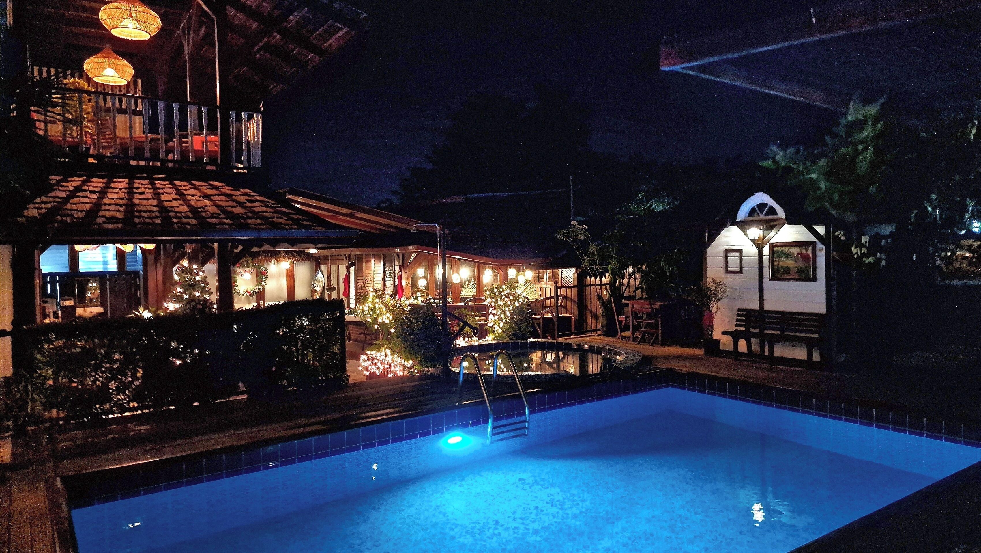 A nighttime view of a hotel with a swimming pool, outdoor lighting, and a small building with a dome.
