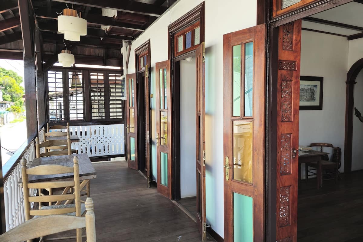 A traditional wooden interior with a staircase, wooden chairs, and a view of the street.