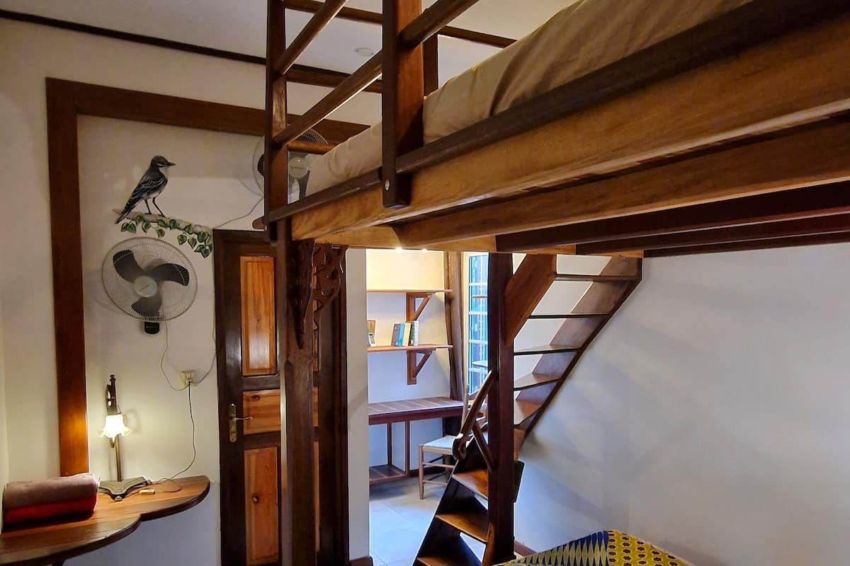 A bunk bed room with a fan, a guitar, and a wooden table.
