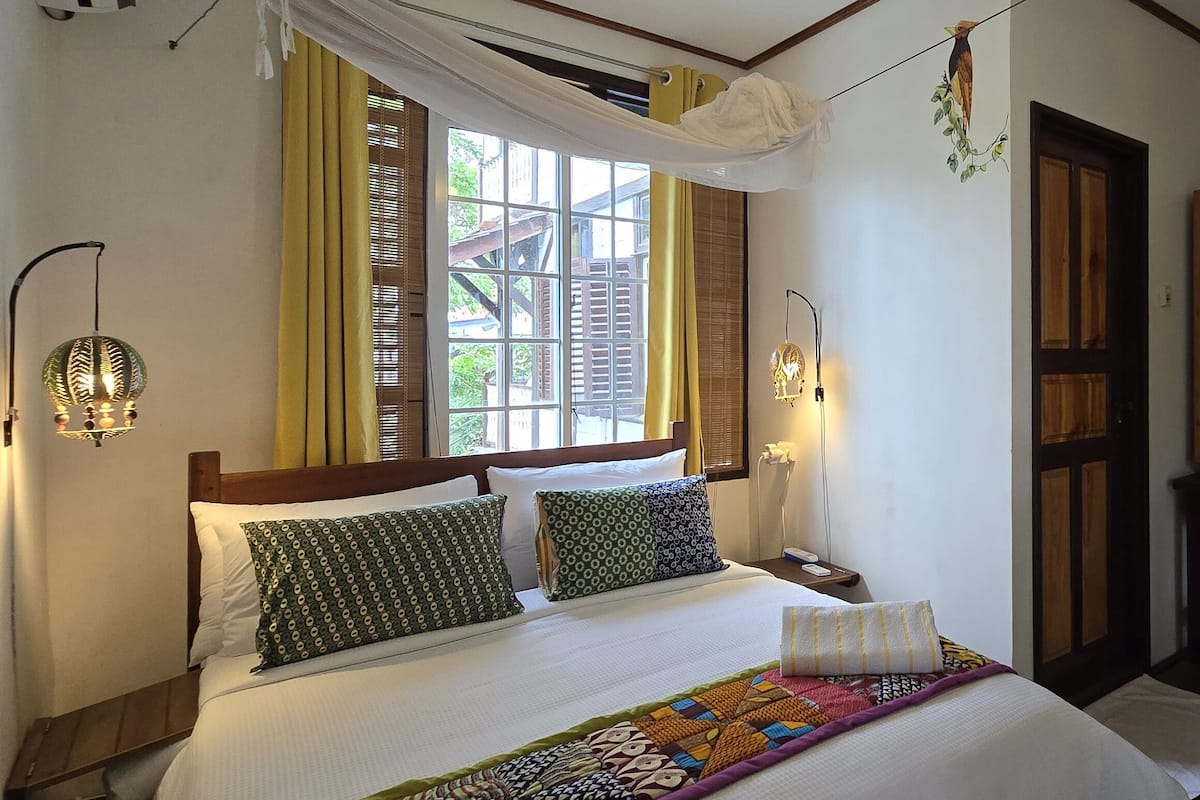 A bed with patterned pillows, a quilt, and a ceiling fan.