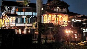 A large, two-story wooden building with a balcony and a thatched roof structure. - Greenheart Boutique Hotel (Paramaribo)