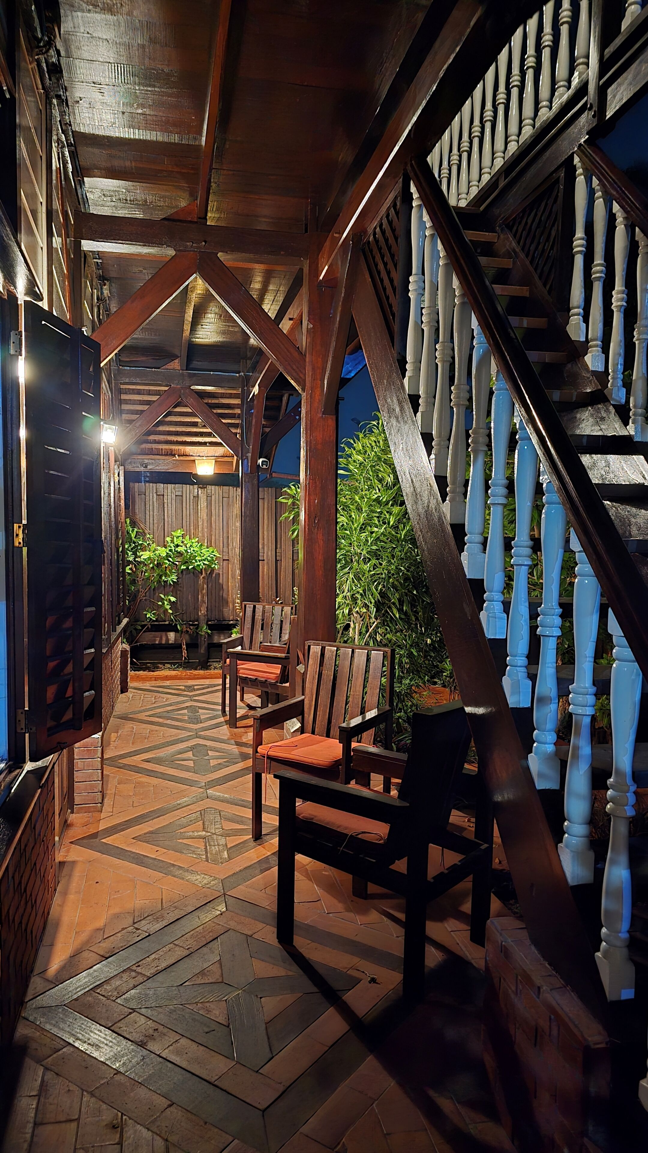 A wooden interior with a staircase, chairs, and a patterned floor.