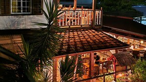 A multi-level outdoor area with a wooden deck, potted plants, and a covered seating area. - Greenheart Boutique Hotel (Paramaribo)