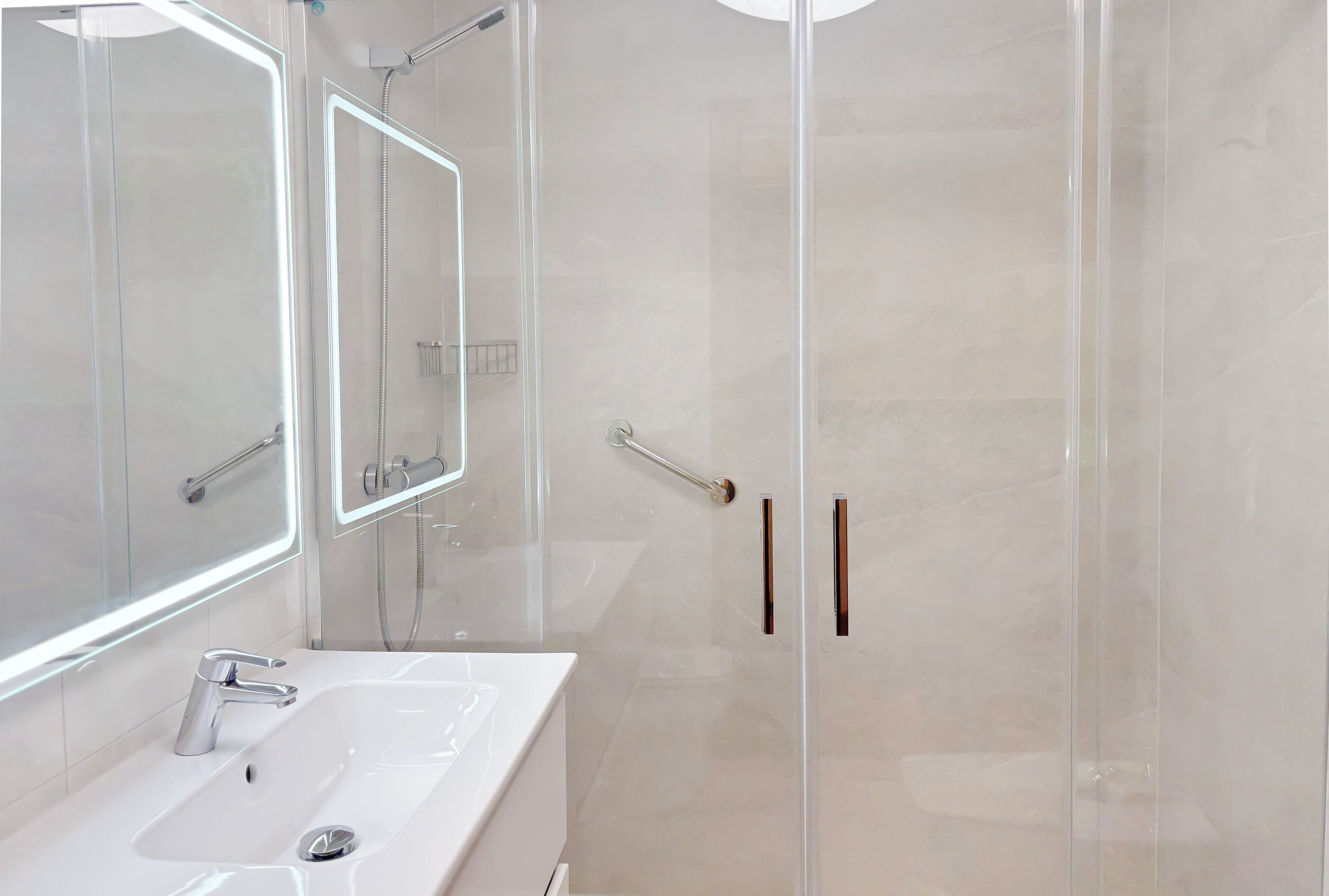 A modern bathroom with a glass-enclosed shower, a white sink, and a large mirror.