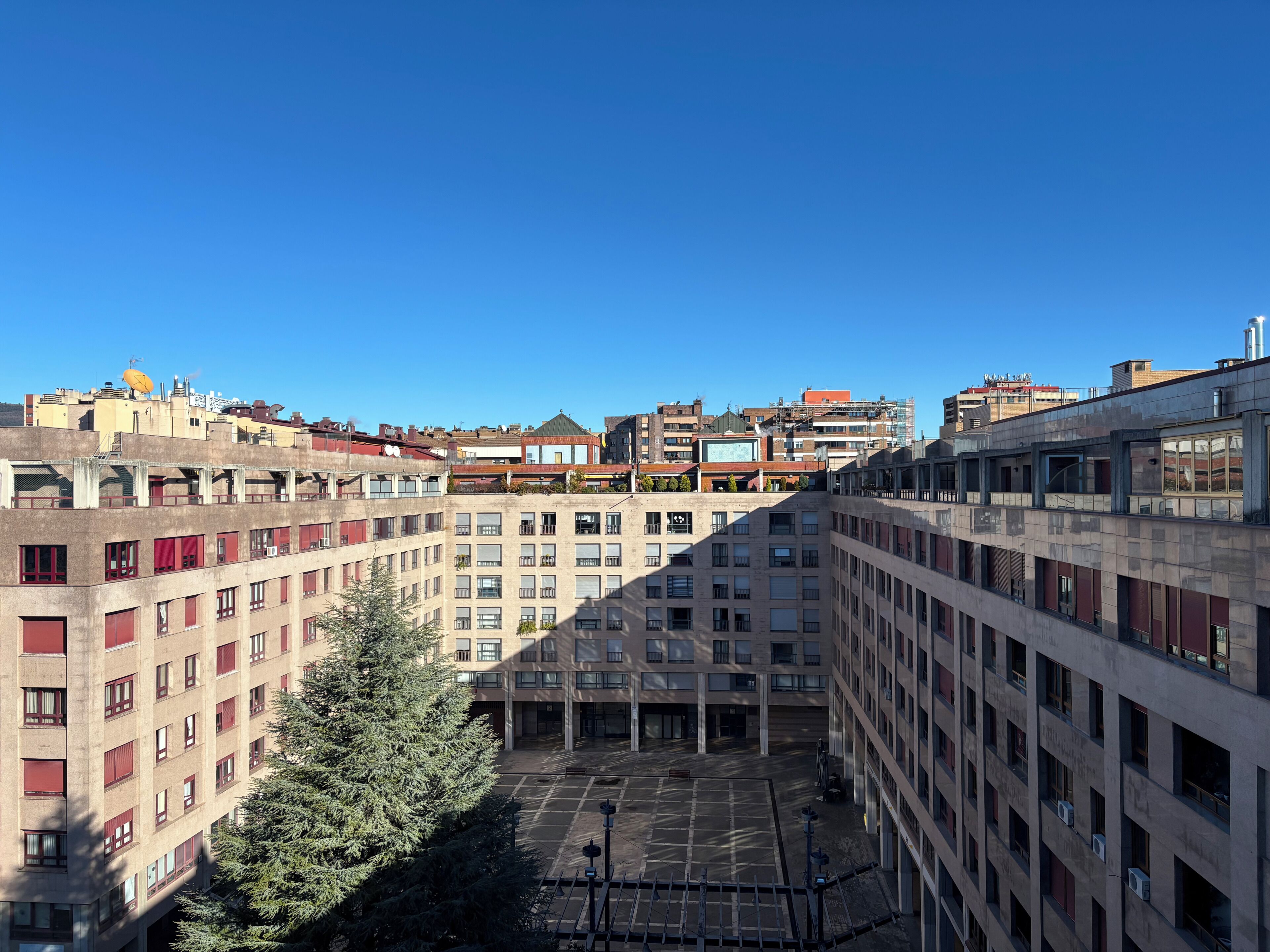 A multi-story building with a courtyard, balconies, and a clear sky.