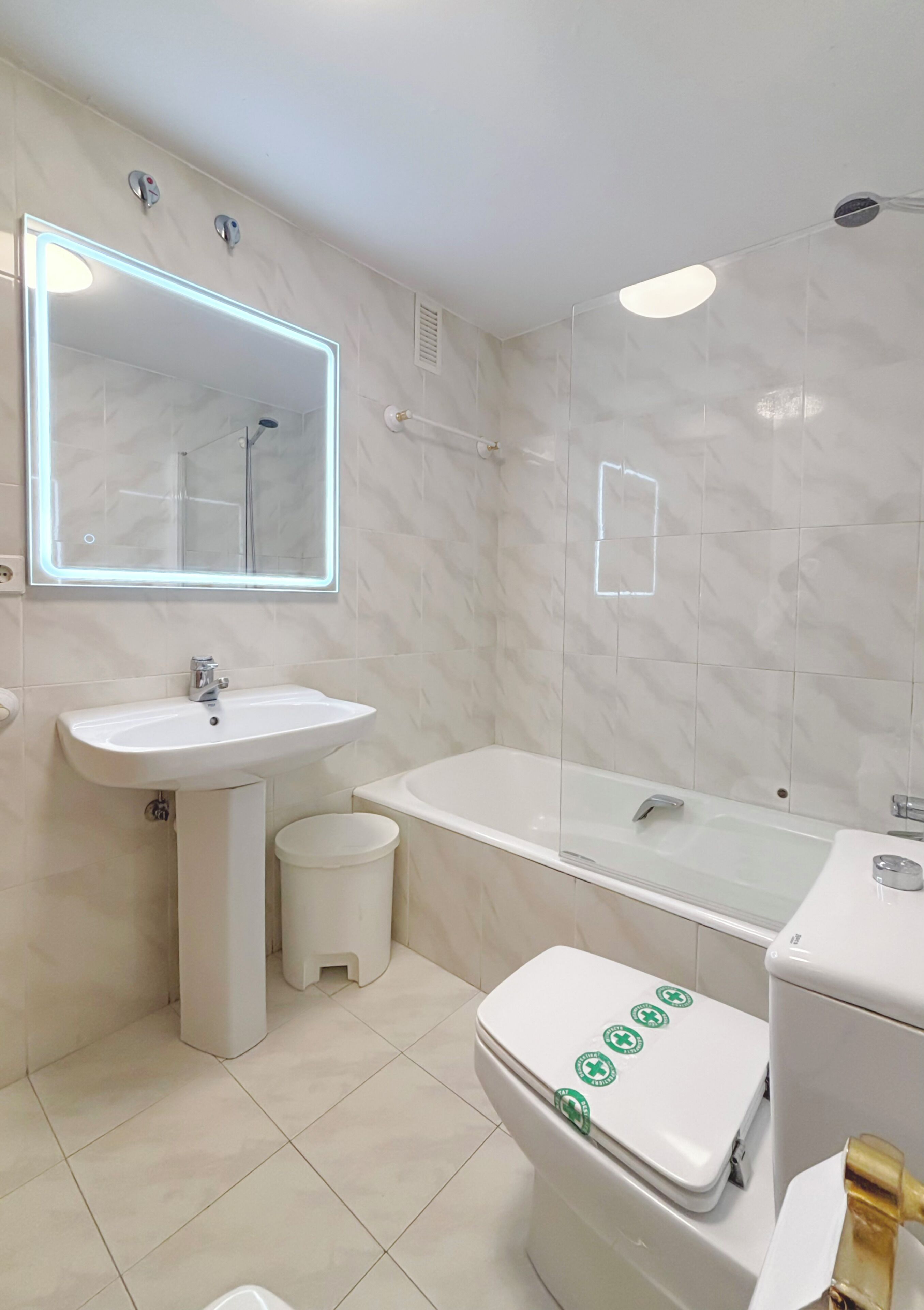 A modern bathroom with a sink, mirror, toilet, and bathtub.