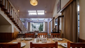 Un comedor con una mesa de madera dispuesta para cuatro personas, sillas y una araña.