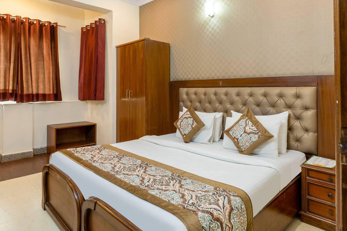 A bedroom with a bed, a wardrobe, a nightstand, a ceiling fan, and a window with curtains.