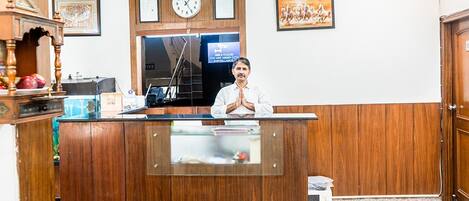 A reception desk with a clock, framed certificates, and a painting of horses.