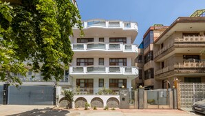 A multi-story residential building with balconies, a gated entrance, and a clear sky. -  SKS Excel Inn (Gurugram)
