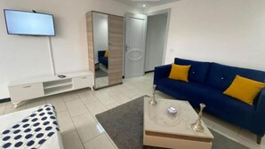 A modern living room with a sofa, coffee table, TV, and a wardrobe.