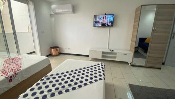 A bedroom with a bed, a TV, a wardrobe, and a small table.