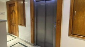 A hallway with a marble floor, wooden doors, and a modern elevator.