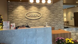 A reception area with a marble counter, a wooden reception desk, and a wall-mounted sign reading "ESMA GUEST HOUSE". - Esma Family GuestHouse (Malang)