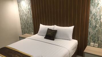 Een hotelkamer met een net opgemaakt bed, een houten hoofdeinde en een wand met een marmerlook.