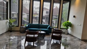 A lobby with a teal sofa, two armchairs, a coffee table, and a potted plant. - Esma Family GuestHouse (Malang)