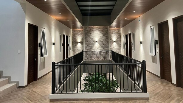 A modern hallway with a central staircase, stone wall accents, and recessed lighting. - Esma Family GuestHouse (Malang)