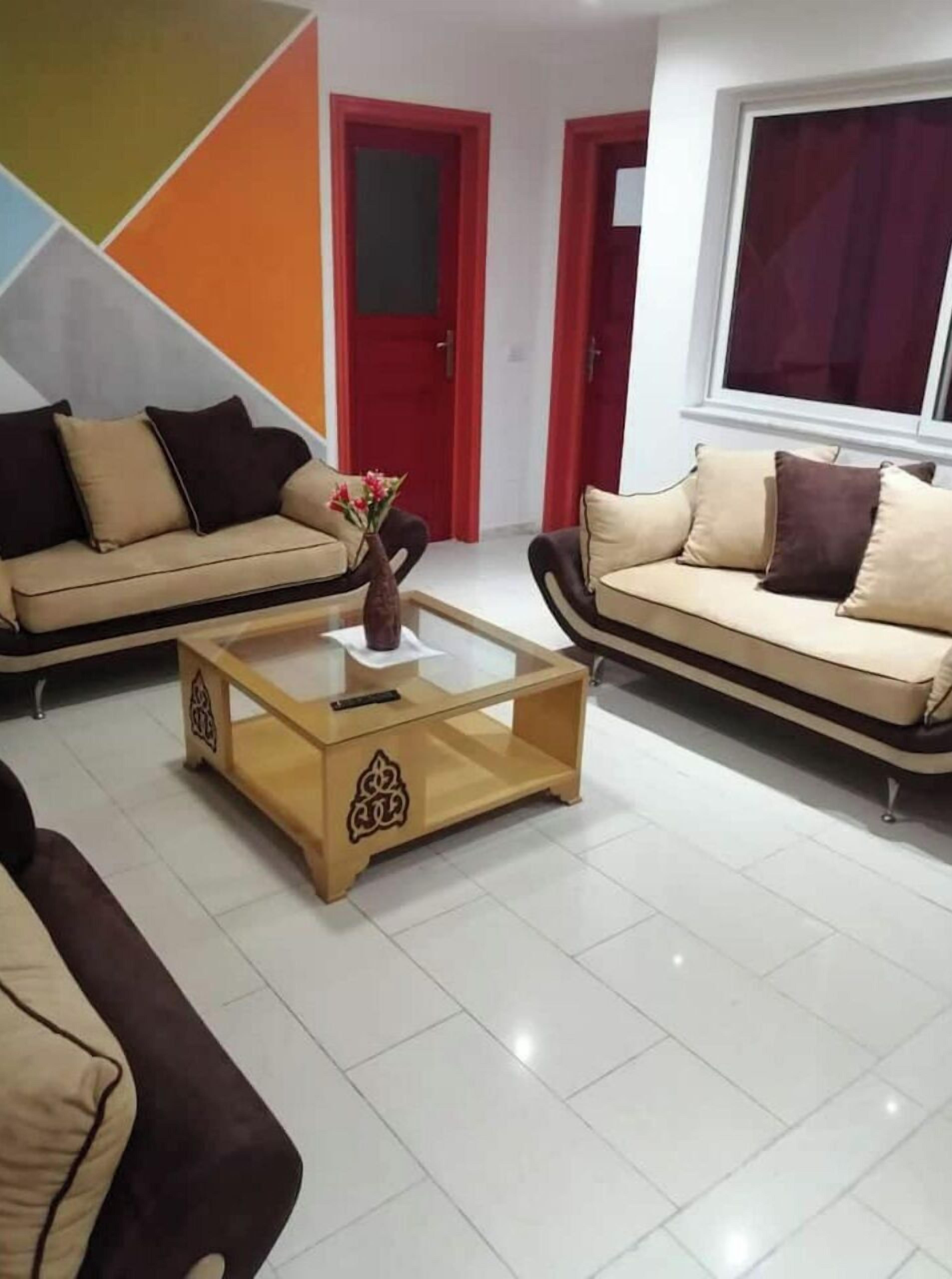 Ein Wohnzimmer mit zwei Sofas, einem Couchtisch und einer roten Tür.