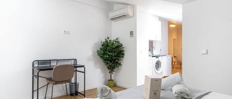 A modern, minimalist bedroom with a bed, a desk, and a washing machine.
