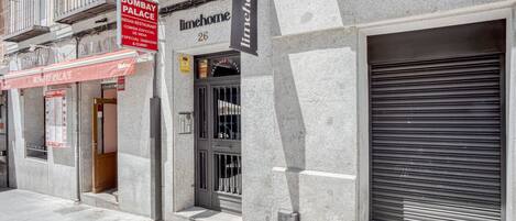A building with a closed shutter, a sign for 'Bombay Palace' restaurant, and a 'limehome' sign.