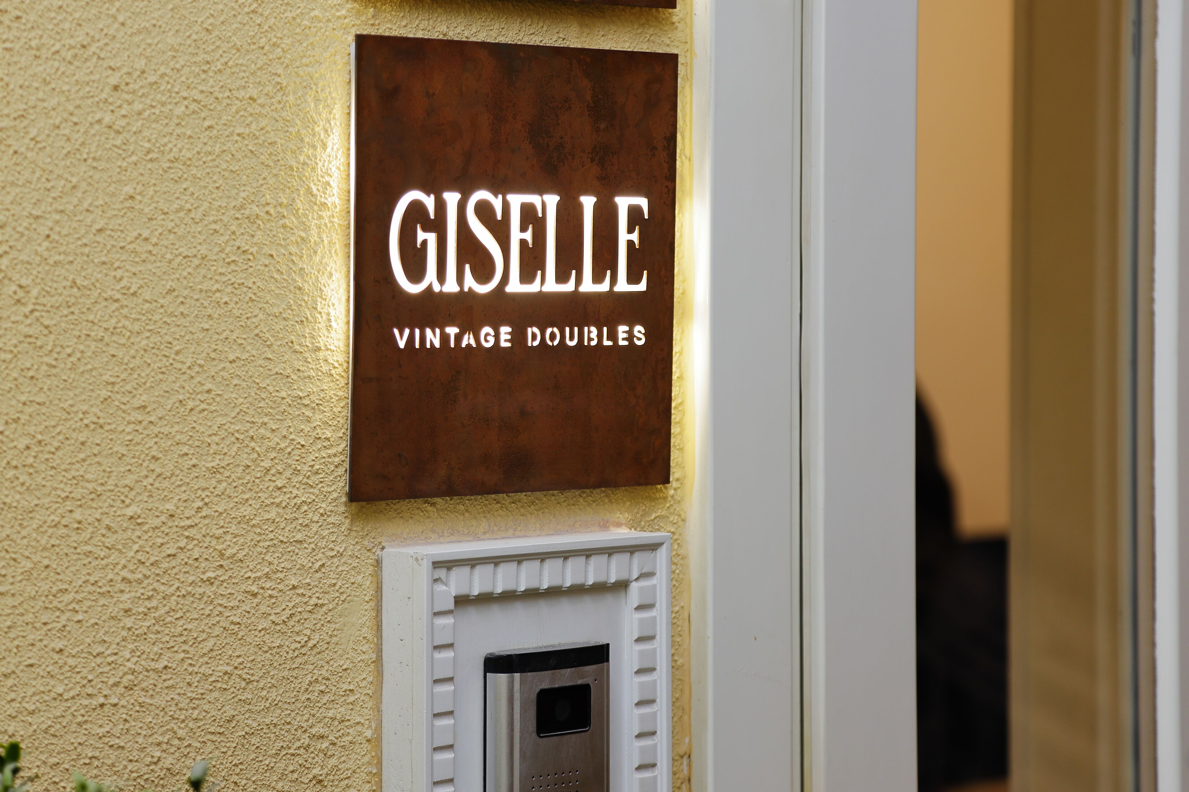 Une enseigne indiquant « Giselle Vintage Doubles » sur un mur à texture.