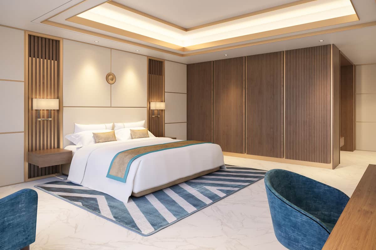 Een moderne slaapkamer met een groot bed, nachtkastjes, een blauwe fauteuil en een houten paneelwand.
