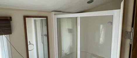 A bathroom with a sink, mirror, and glass shower enclosure.
