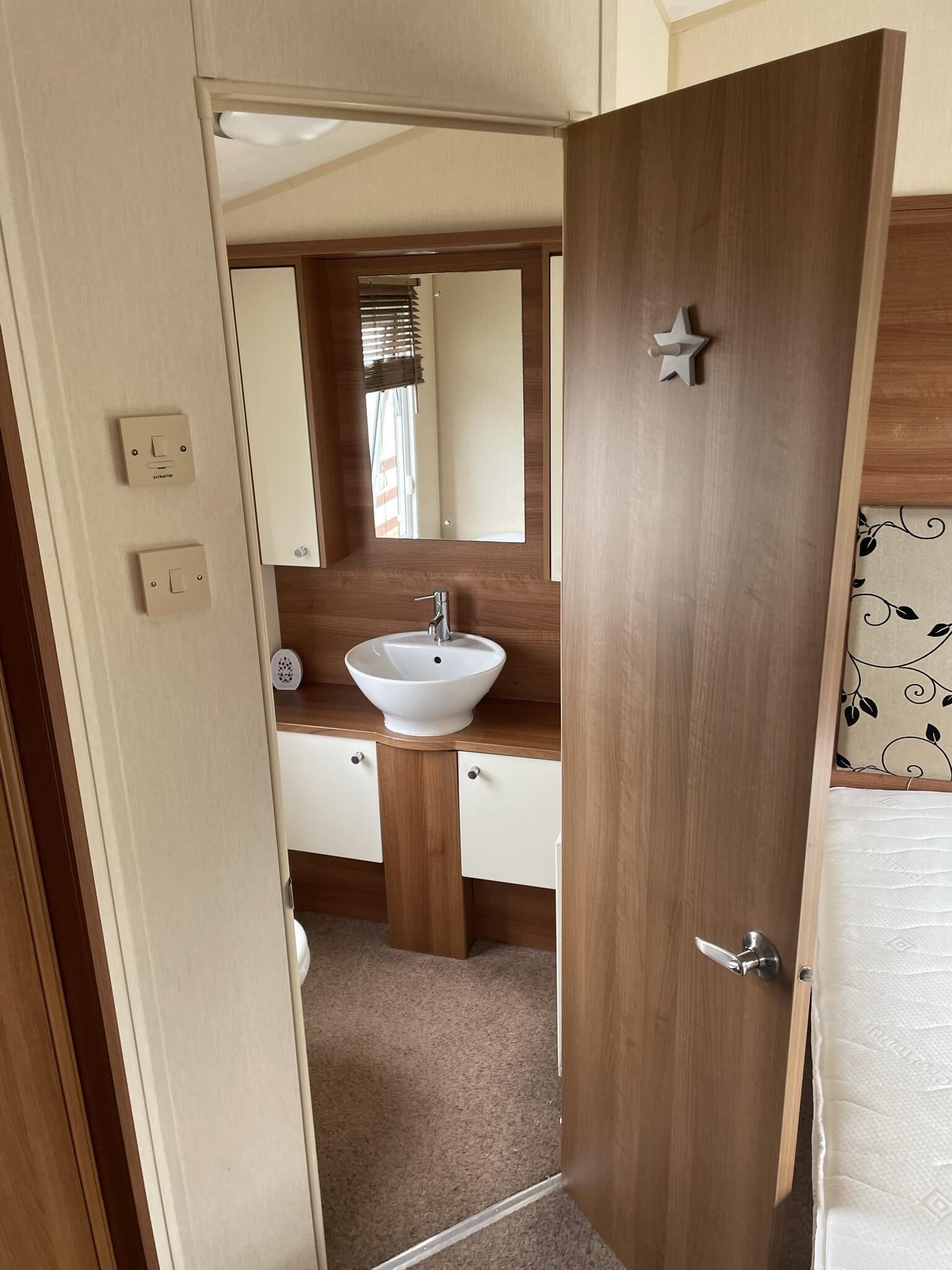A bathroom with a wooden vanity, a white sink, and a mirror.