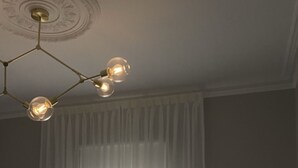 Une chambre à coucher avec un lit, un lustre et une fenêtre ornée de rideaux légers.