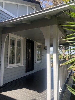 Guests can enjoy a covered porch with a dark door and two windows.