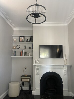 Cozy living room with a classic design, featuring a fireplace, flat-screen TV, and vintage radio.