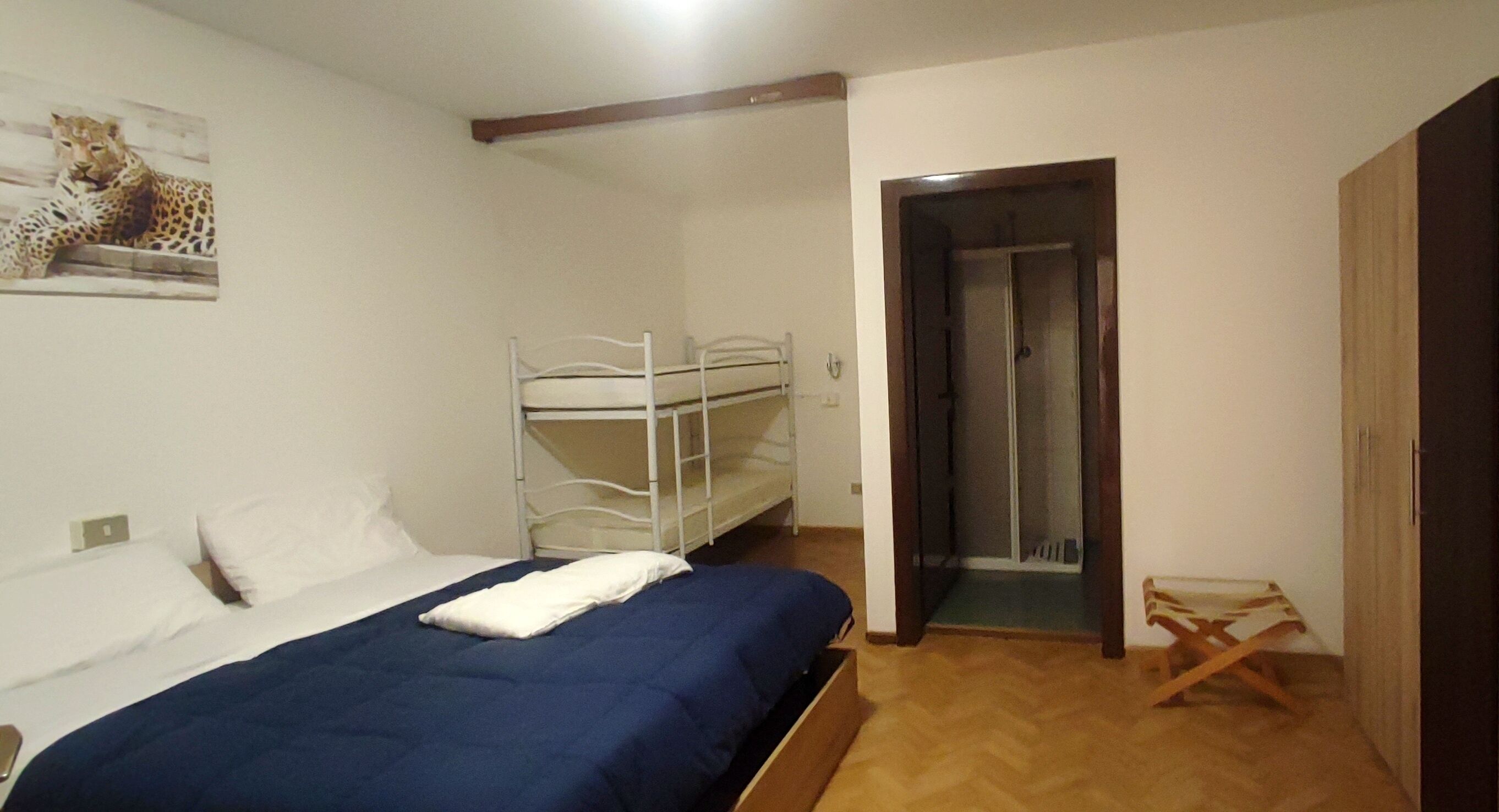 A bedroom with bunk beds, a shower, and a wooden floor.
