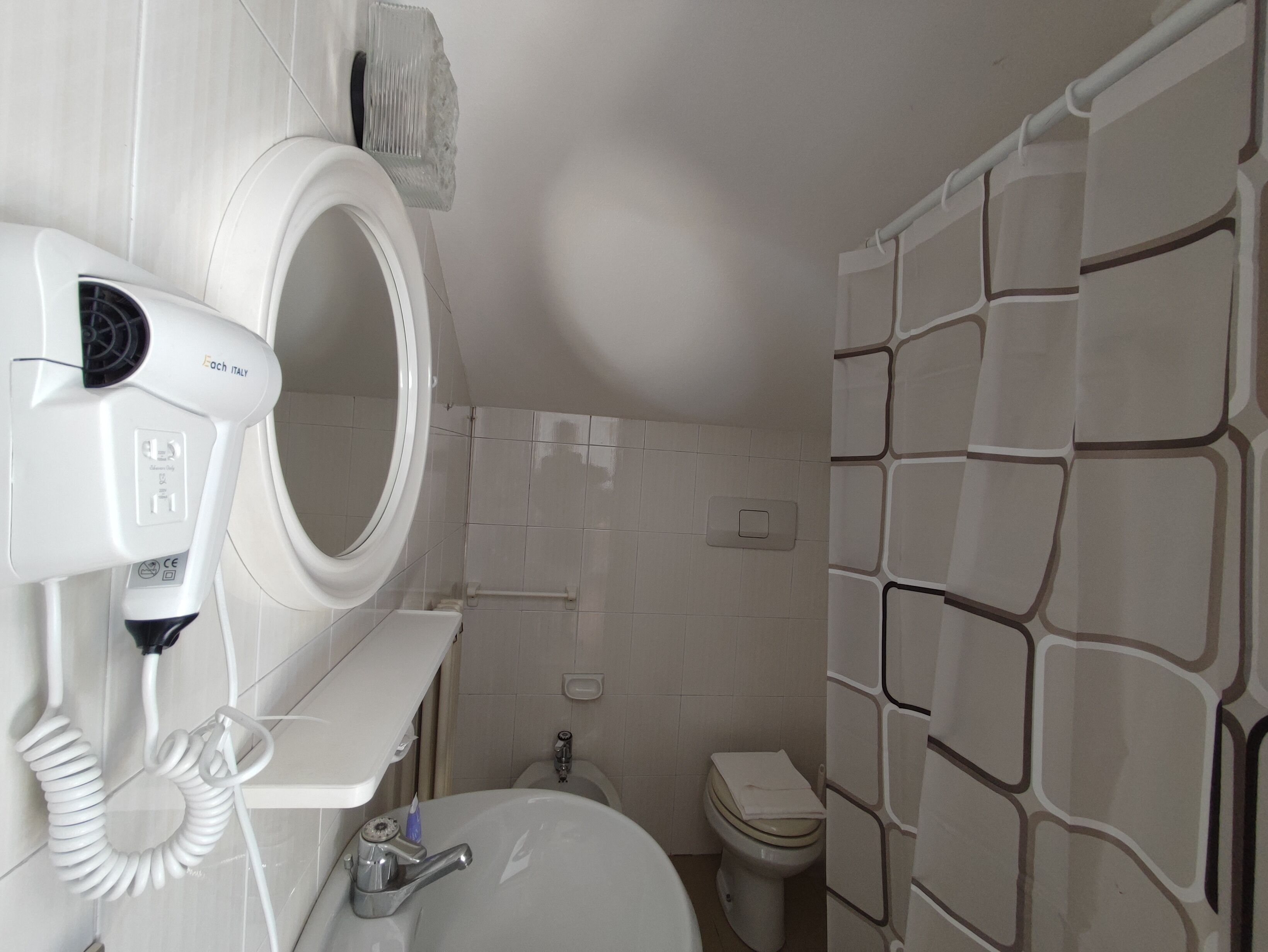 A bathroom with a white sink, a mirror, a hairdryer, and a toilet.