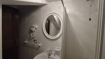 A bathroom with a white sink, a mirror, and a hairdryer mounted on the wall.