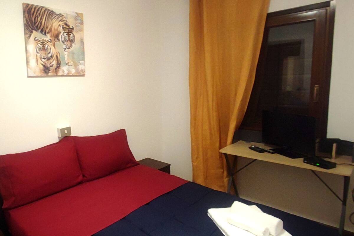 A hotel room with a bed, a TV, and a painting of tigers on the wall.