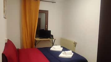 Una stanza piccola con un letto, una scrivania, una televisione e un termosifone.