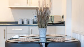 A modern kitchen with white cabinets, a black countertop, and a round table with two black chairs. - No14 (Mansfield)