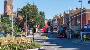 A street scene with a red double-decker bus, a McDonald's, and a building with a tower. - Impeccable Studio Apartment in West London (London)