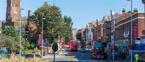 A street scene with a red double-decker bus, a McDonald's, and a building with a tower.