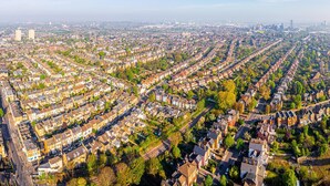 An aerial view of a residential area with rows of houses, roads, and a distant city skyline. - Impeccable Studio Apartment in West London (London)